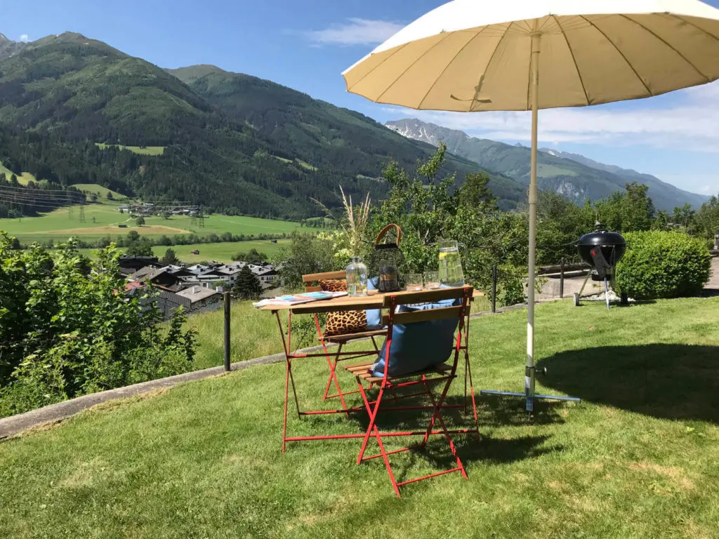 Sonnige Liegewiese mit Tisch, Sonnenschirm und Grill