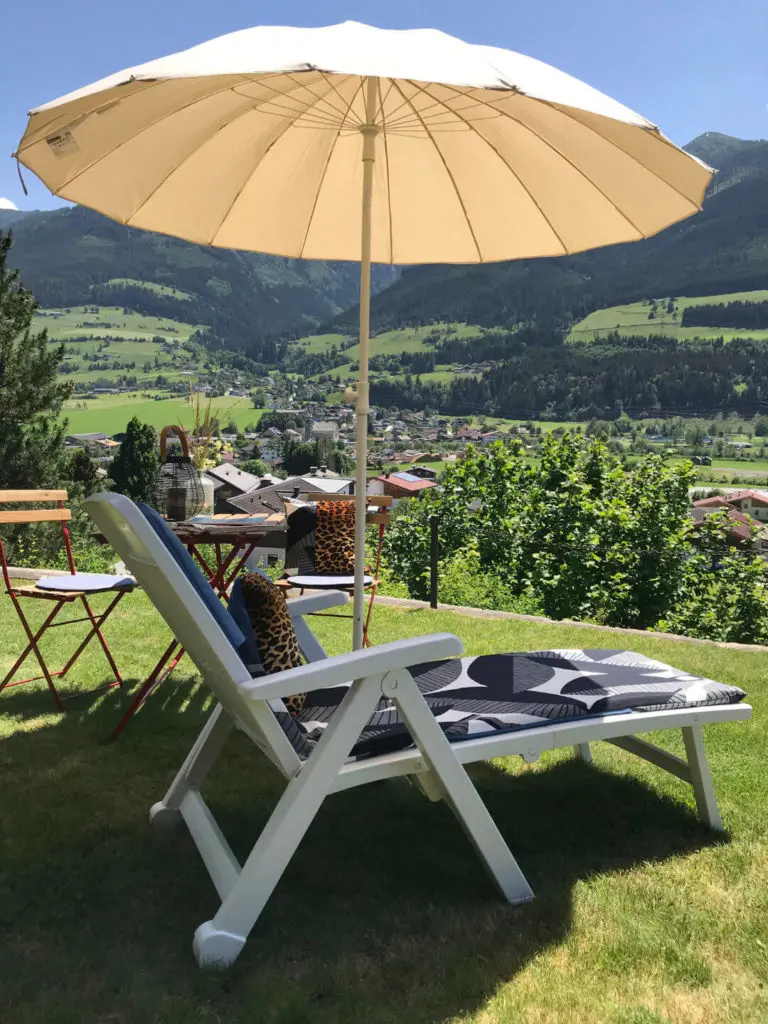 Sonnige Liegewiese mit Tisch, Sonnenschirm und Sonnenliege